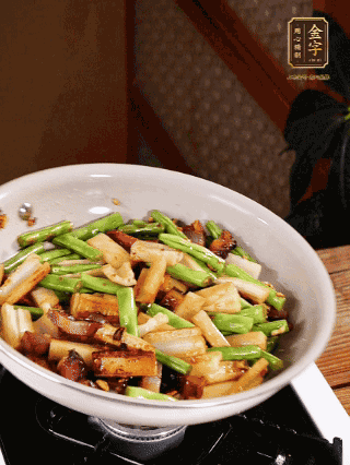 油熱下蒜末、干辣椒、醬肉煸炒出香味，依次下藕條、豆角翻炒均勻